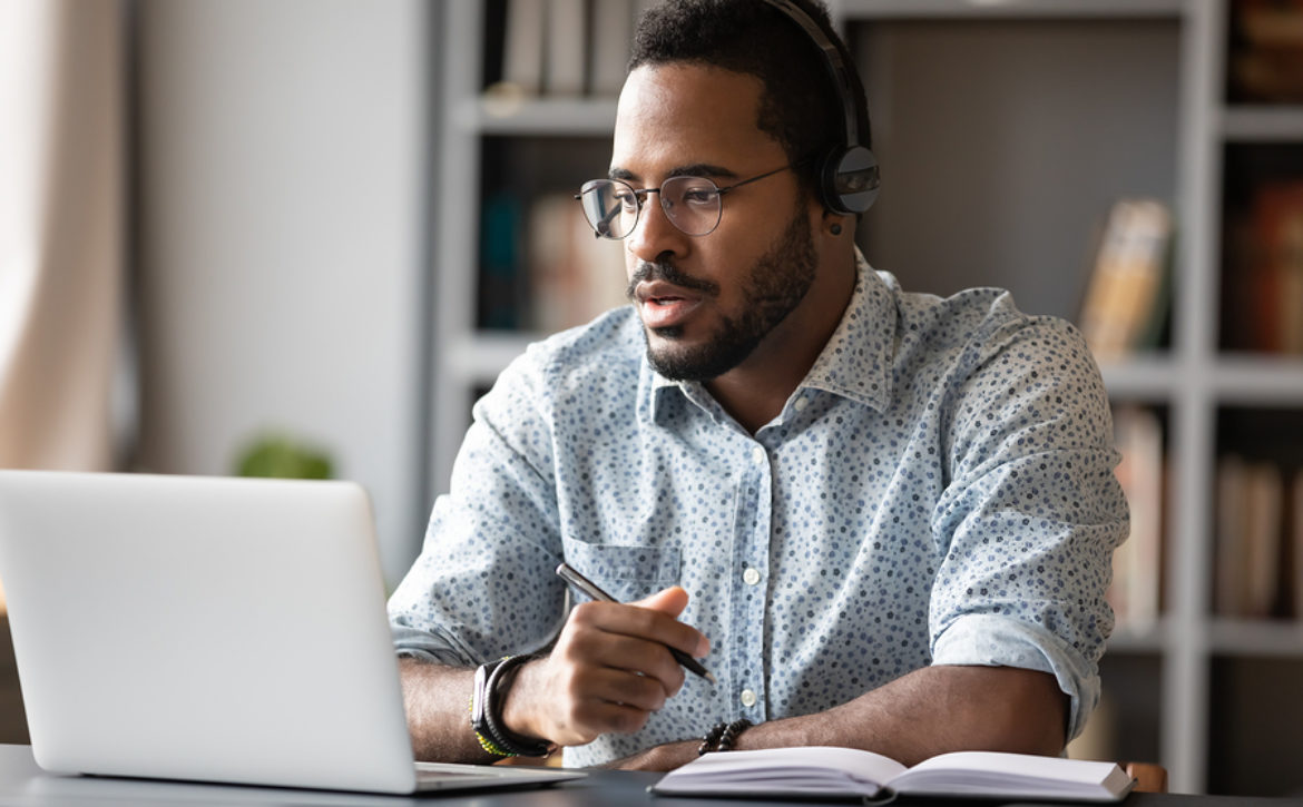 Focused African Businessman Wear Headphones Study Online Watchin